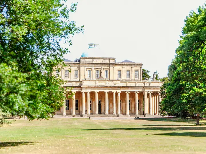 The Pittville Pump Room in Cheltenham, framed by summer trees